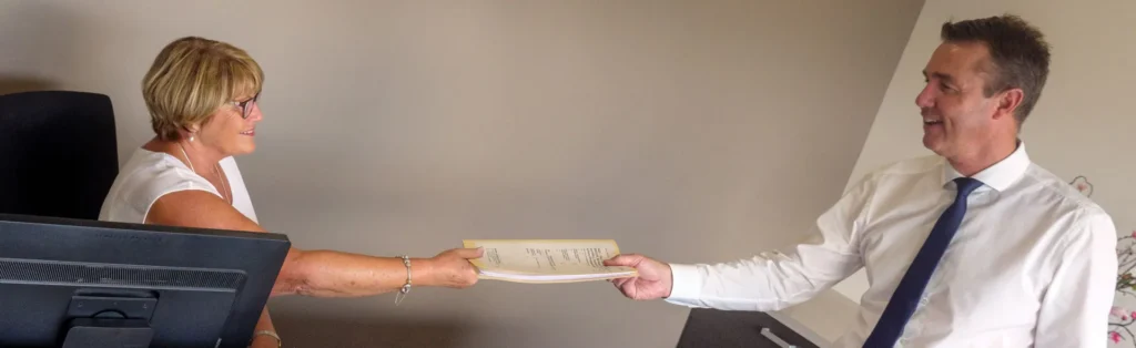 A solicitor handing documents to a client across the desk